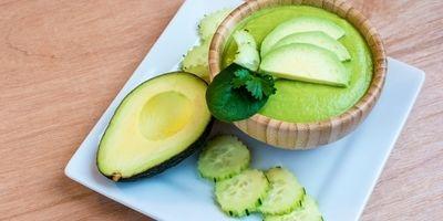 A green smoothie garnished with fresh avocado and cucumber slices