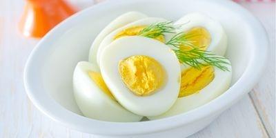 Hard boiled eggs sliced in half in a white bowl garnished with fresh dill.
