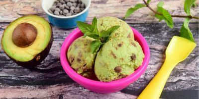 Three scoops of avocado chip ice cream in a pink bowl garnished with a fresh mint leaf.