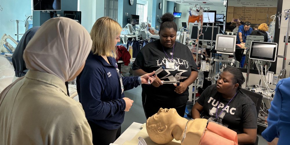 Claire Ward, Respiratory Therapy class of 2025, assists high school students in the Simulation ICU