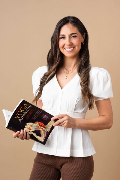 Dr. Rebecca Alexander is standing, holding a book about yoga