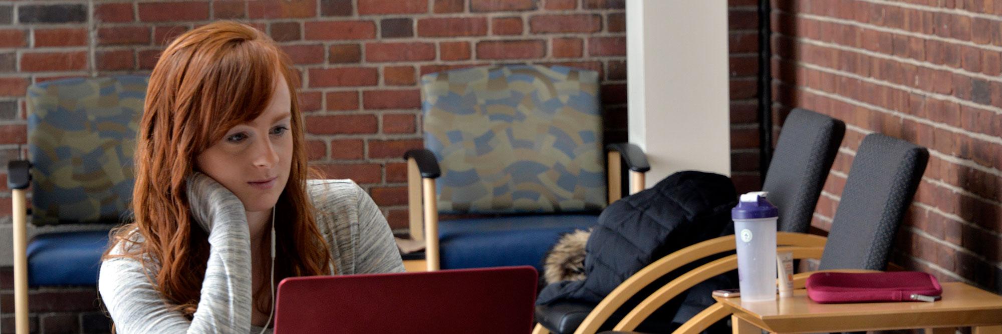 Student in front of laptop within a space on SUNY Upstate's campus