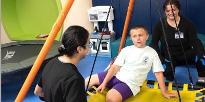Two students or technicians smiling while a child swings on a swing