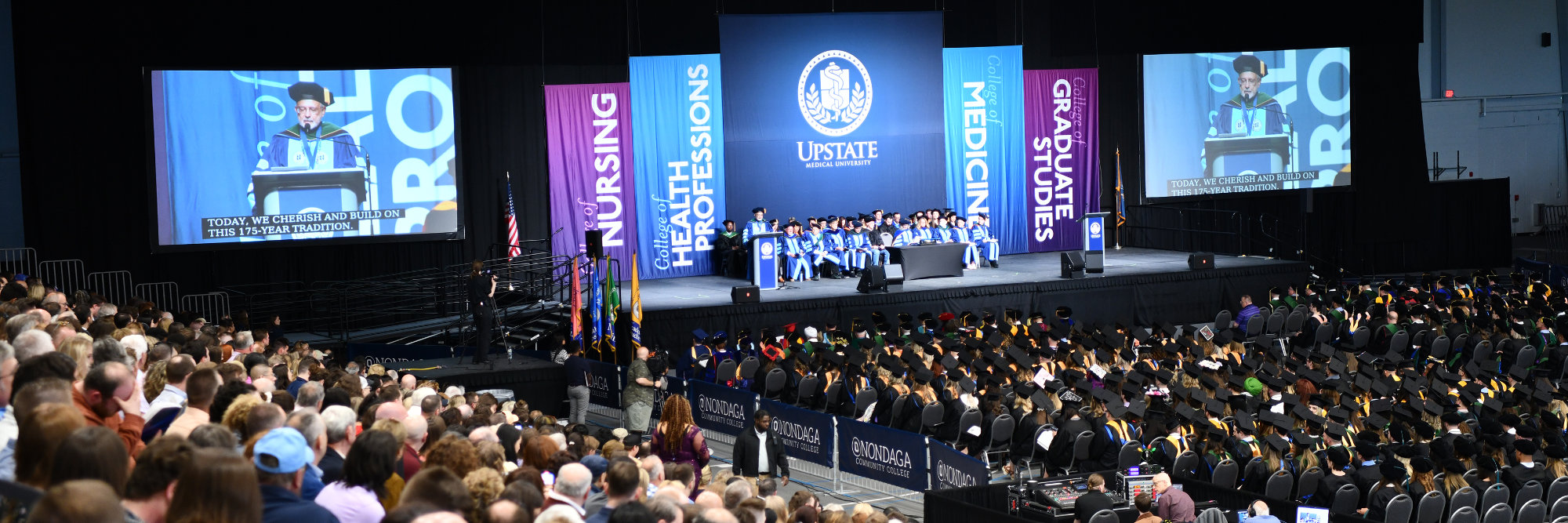 The president of Upstate, Dr. Dewan, speaks at the 2023 Commencement while students and audience watch.