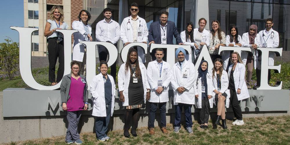 Photo of hospitalist team outside beside giant Upstate logo
