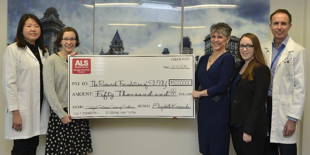 ALS Clinic staff holding up a giant check worth $50,000