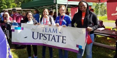 Four students holding up a Team Upstate banner at the "Walk to Defeat ALS