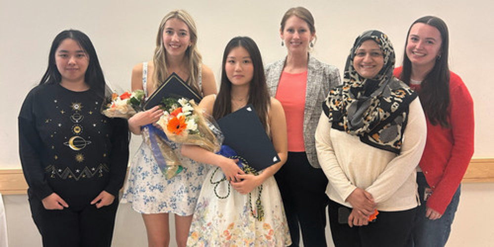 Group of women standing in front of a white wall.