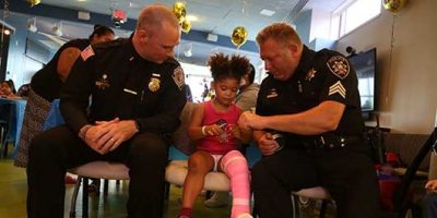 Onondaga County Sheriff's Office Lieutenant Christopher Koeppe and Sergeant Jon Seeber present Sarai, an Upstate Golisano Children's Hospital patient, an official sheriff's badge at the second-annual Onondaga County Sheriff's Pizza Party