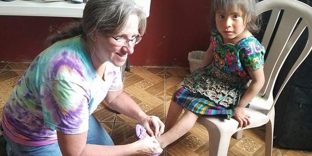 Sue Thomas putting socks on a child