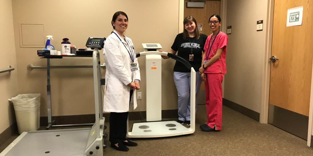 Bariatric Surgery Division Chief Flavia C. Soto, MD, (left) stands with Upstate’s new body composition analyzer, with medical office assistants Tamara Jacobs and Candace Brown