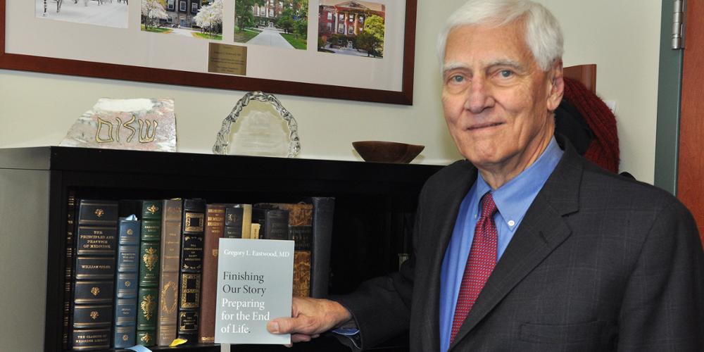 Dr. Gregory Eastwood holds a copy of his new book, "Finishing Our Story: Preparing for the End of Life," in his office.