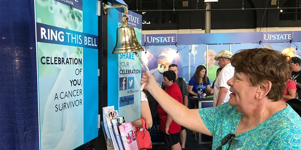 A fairgoer rings the cancer survivor bell at the Upstate Cancer Center.