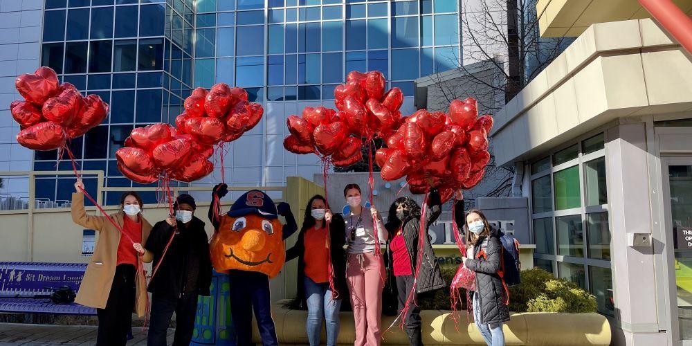 VALENTINE’S DAY DELIVERY: Otto the Orange joins staffers from SU’s Newhouse School of Public Communications in delivering red heart balloons to patients at Upstate Golisano Children’s Hospital on Valentine’s Day.