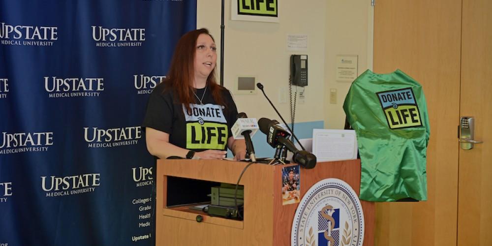 RAISING AWARENESS: Gina Richardson, whose son Ty’Sean was struck and killed by a car in December 2022, speaks at an Upstate Donate Life awareness event April 19 urging people to sign up to be organ donors. She said her son loved superheroes and became one as his organ and tissue donation benefitted the lives of more than a dozen people. The superhero cape on the podium is now given to parents of pediatric donors in a nod to Ty’Sean’s family’s decision to donate.