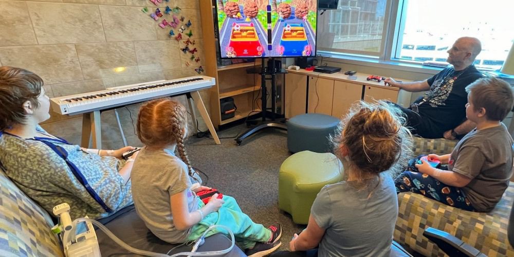 HEALTHY CHILDREN, HAPPY CHILDREN: Gaming and Technology Specialist Brad Taylor, right, a member of the Upstate Golisano Children’s Hospital Child Life team, oversees a video game break with patients.  March is Child Life Month. The Child Life team features more than a dozen specially certified members, including music and art therapists.