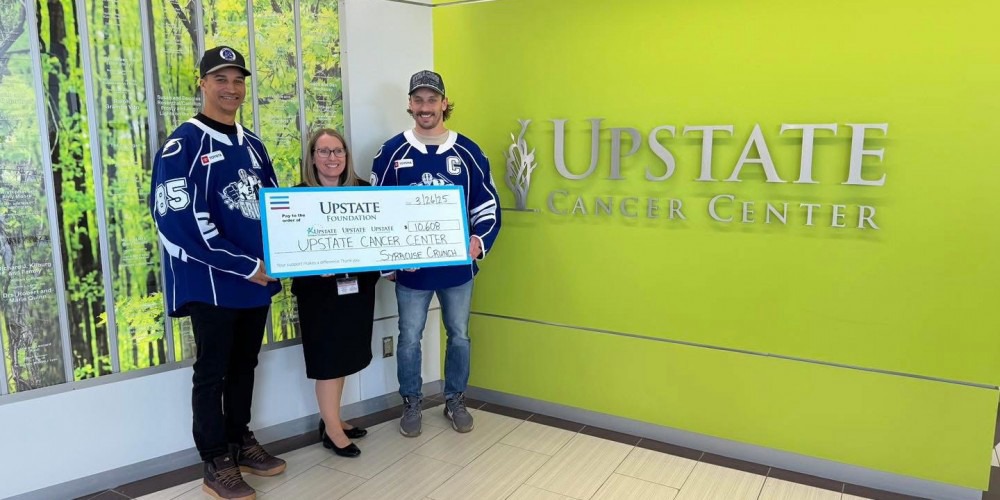CRUNCH CASH: Syracuse Crunch members Daniel Walcott, left and Gabriel Dumont present Upstate Cancer Center Associate Administrator Jennifer Loguidice with a check for more than $10,000 that was raised this season at Crunch games to benefit Upstate’s cancer programming.