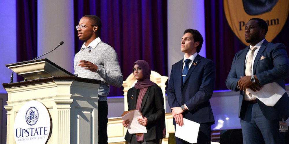 HONORING THOSE WHO GAVE: Upstate students, from left, Tariq Martin, Safa Nadeem, Dante Whitmire and Stevie Tchako-Tchokouassi, participate in the Anatomical Gift Program memorial service April 26 recognizing more than 200 individuals who donated their bodies to further medical education. More than 500 friends and family members filled Hendricks Chapel for the service.