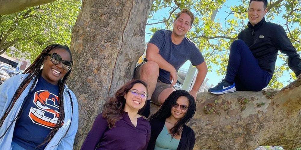 Resident group photo at a tree with 2 people perched on the limb