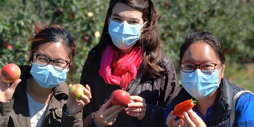 Students holding apples at an orchard