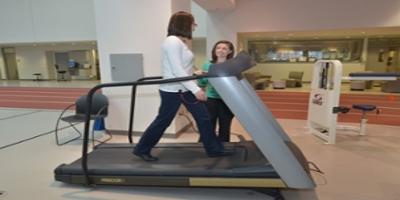 A therapist monitoring a patient on a treadmill