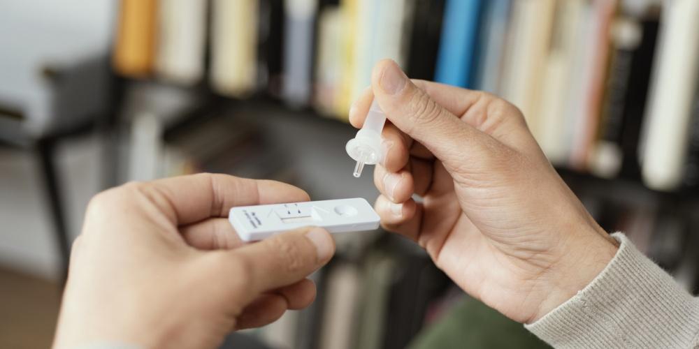 Man holding vial for at-home Covid-19 test kit
