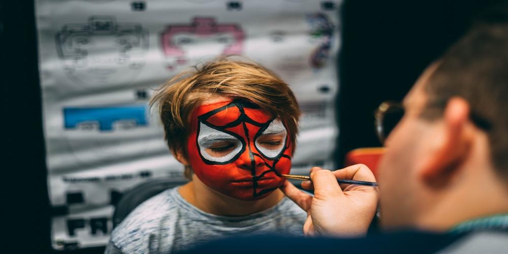 Boy having his face painted.