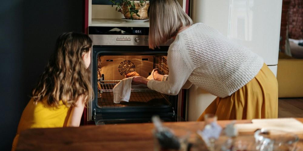 Grandma and granddaughter putting turkey in the oven.