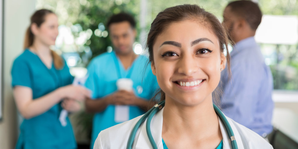 Woman med student smiling in front of other med students talking