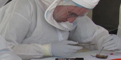 man in lab outfit disecting a mouse