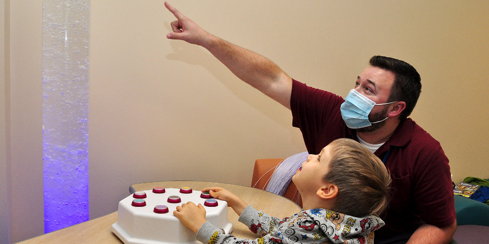 Upstate employee and child playing with button toy