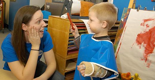 Pediatric patient discusses his painting to staff member