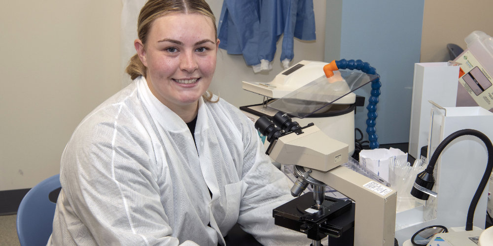 Caitlin Flanagan in the lab with a microscope