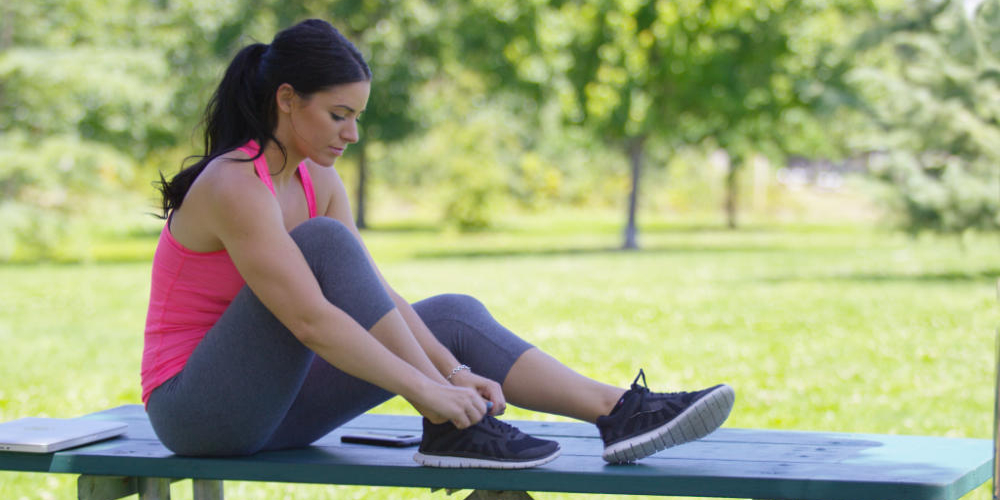 Jogger lacing up sneakers on a bench