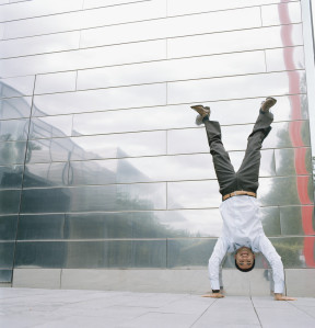 Business man doing handstand outside in front of office building