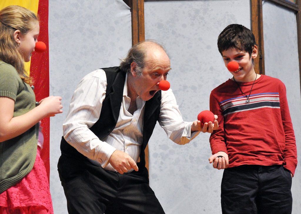DSC_0224 Zoe and Michael share the stage and red noses with puppeteer and magician Geoff Navias at a performance for the Margaret Wiliiams Center.