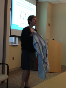 Nurse manager Becky Mesmer uses a hospital gown as a prop during I Am The Patient Experience training on Thursday, Aug. 1.