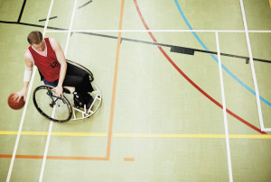 wheelchair bound man bounces basketball. Shot from above.