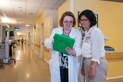 Brain injury medicine specialist Bernadette Dunn, MD, discusses a patient's progress with nurse manager Virginia Castro.