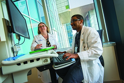 Brain injury medicine specialist Bernadette Dunn, MD, discusses a case with neurosurgery resident Khalid Khalid, MBBS. Dunn is also an associate professor of physical medicine and rehabilitation who trains residents and medical and other students.