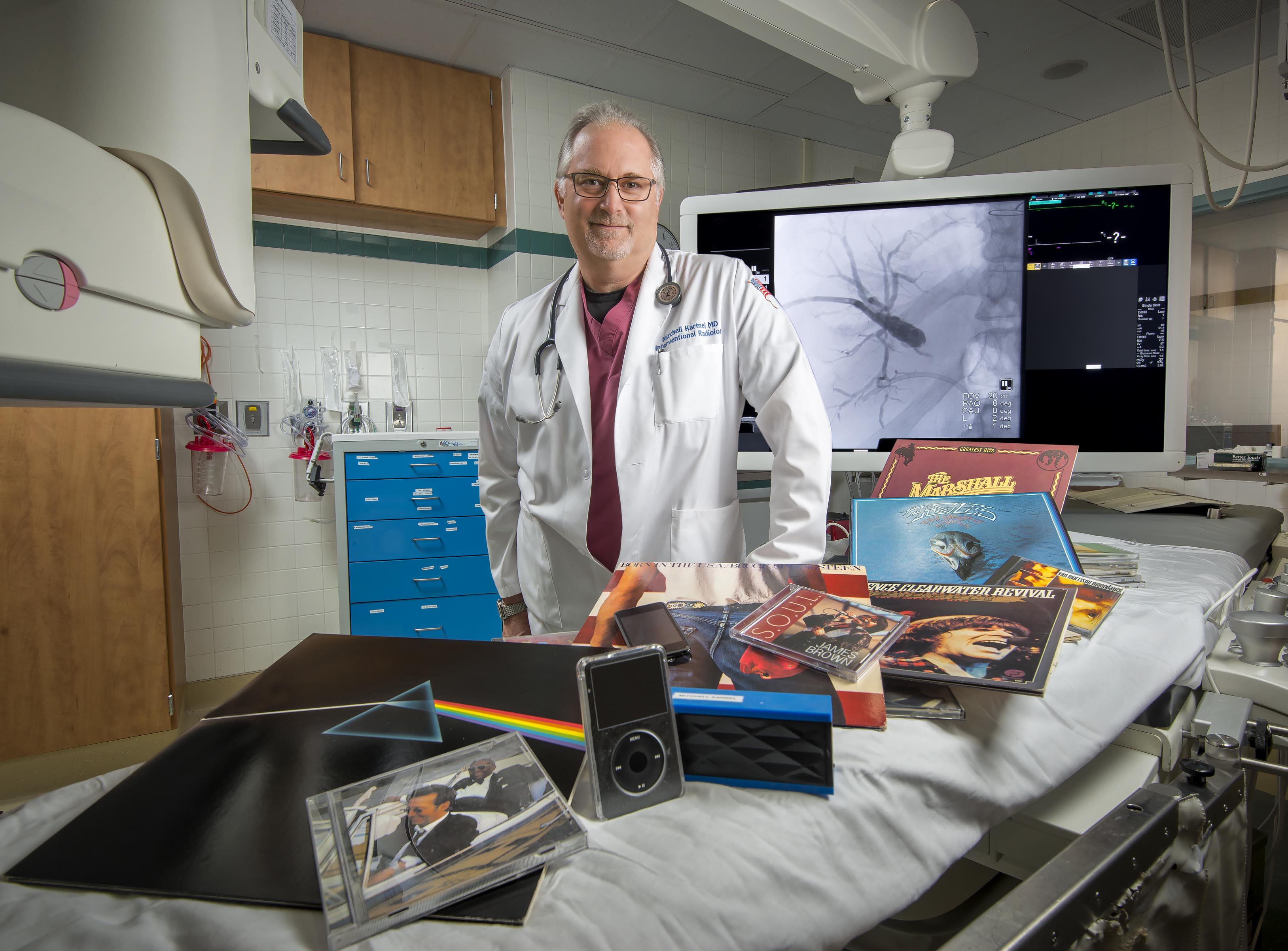 Mitchell Karmel, MD, in an operating room in the radiology suite with a sampling of the thousands of albums he owns. (PHOTO BY ROBERT MESCAVAGE)