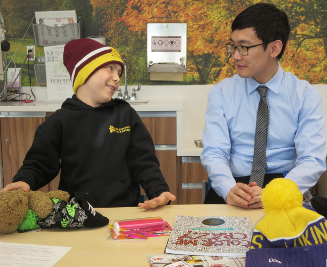 Medical student Shunqing Zhang lets cancer patient Connor Stanton, 10, choose from a collection of New Era hats. The youngster (son of Rebecca Quilty of Whitney Point) was especially pleased to find one for his favorite NFL team, the Seattle Seahawks. (PHOTO BY JIM McKEEVER)