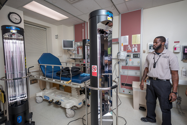 Tavontae Cannon, a member of Upstate's housekeeping staff, inspects the new ultraviolet cleaning towers at Upstate University Hospital.(PHOTO BY ROBERT MESCAVAGE)