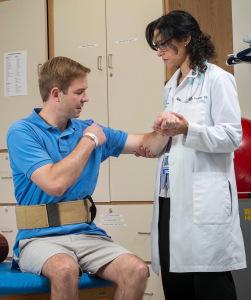 Reger speaks with Shernaz Hurlong, DO, the physician overseeing his rehabilitation, at a session in September. (PHOTO BY ROBERT MESCAVAGE)