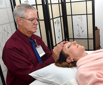 Bob Crandall provides Reiki for Bailey Colvin, a patient at the Upstate Cancer Center. (PHOTOS BY DEBORAH REXINE)
