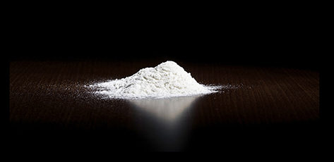 White powderlokking like cocain on dark brown empty Kitchen table