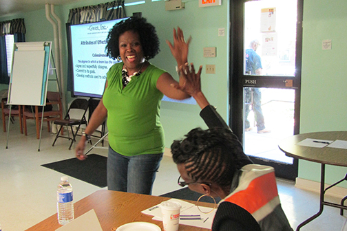 Guest instructor Gwen Webber-McLeod (left) high-fives Tara Harris, a resident health advocate who initiated the parenting classes in the Healthy Neighbors program. (PHOTO BY SUSAN KEETER)