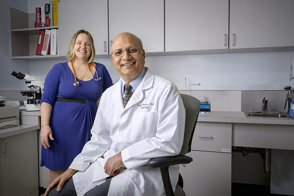 Kazim Chohan, PhD (seated), leads Upstate‘s Male Fertility Preservation Program, which came about through the efforts of Chohan and colleagues including pediatric oncologist Jody Sima, MD (standing), (and, not pictured) urologist JC Trussell, MD, oncologist Rahul Seth, DO, and pathology chair Robert Corona Jr., DO. (PHOTO BY ROBERT MESCAVAGE)