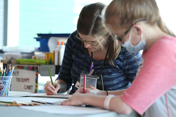 Alexis works on an art project with Fazzini. Upstate Golisano Children's Hospital also holds exhibitions of art created by patients.