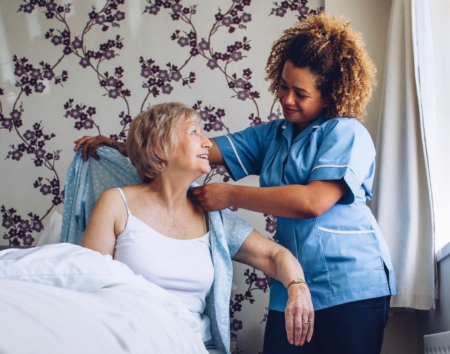 Home caregiver dressing senior